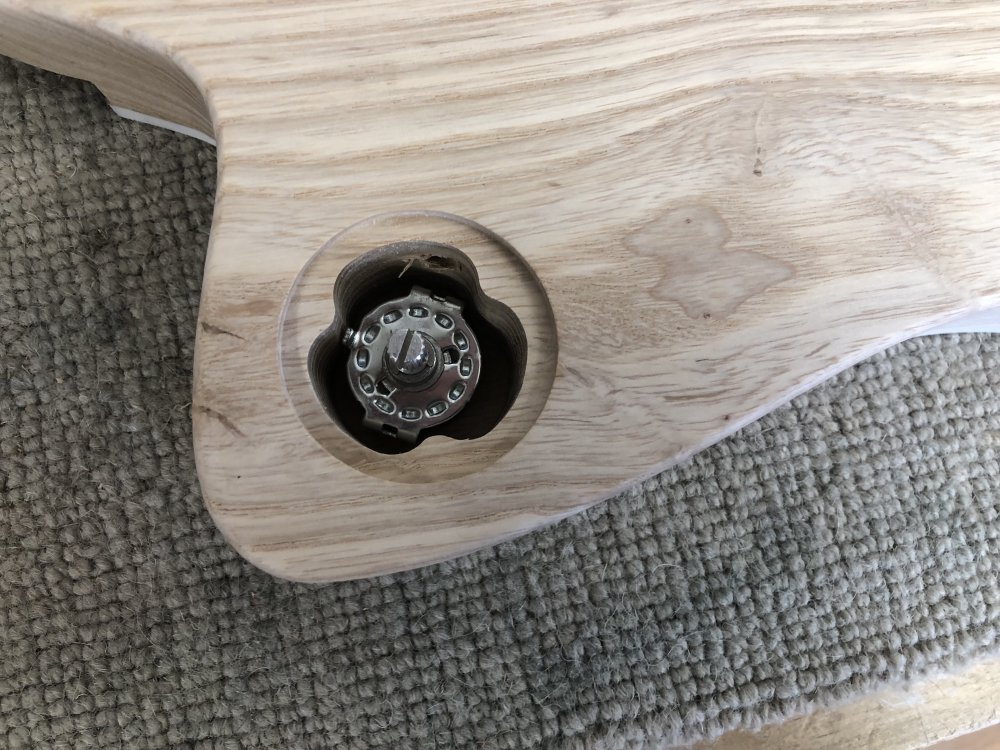 A photo of a rotary switch sitting in the guitar-body cavity in which it will eventually live, showing there's on a few millimetres clearance on each side.
