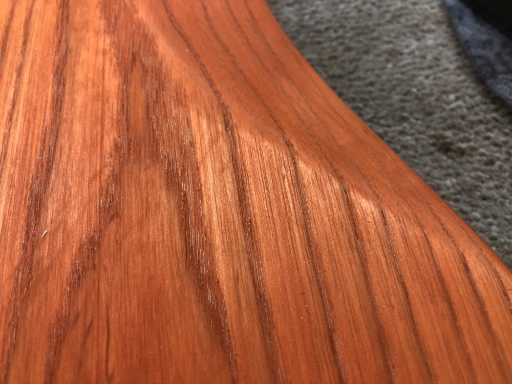 A close up on the back of the guitar near the belly-cutaway, where you can see a scratch mark running across the grain of teh wood.