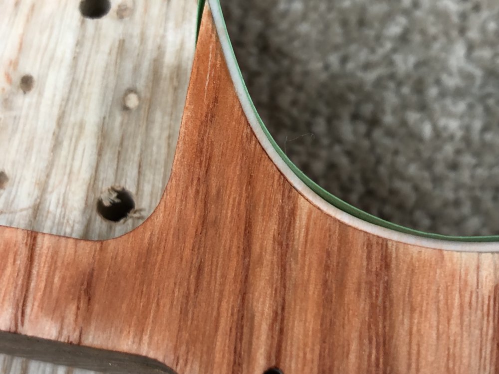 A close up of the guitar body showing a section of the plastic binding near the neck pocket, where you can just see a hairline gap between the wood and the binding.