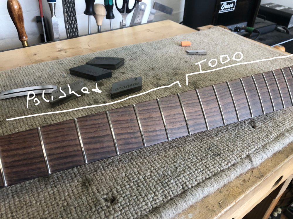 A photo of the fretboard angled to catch the workshop light in the frets. Those to the left the light is just in the middle of the fret as it acts more like a mirror, and those on the right are all just generally lit, not being so reflective.