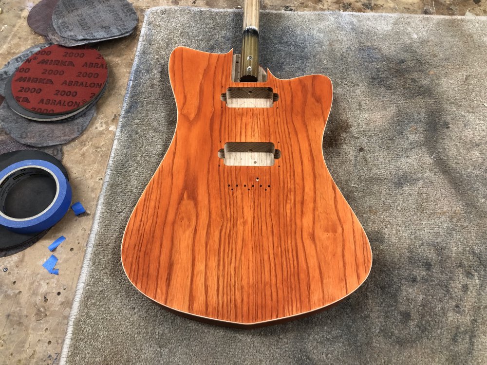 A photo of the front of the guitar body on the workbench, with the front now totally stained a rich orange again.