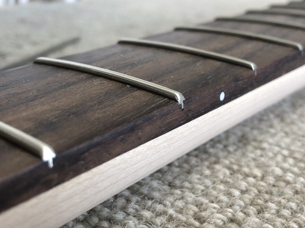 A close up of a couple of the fret-ends, showing how the edges have been filed flush with the fretboard, leading to straight edges on the edge profile.