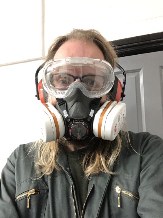 A selfie-photo of me wearing overalls, eye projectors over my glasses, a respirator and ear defenders.