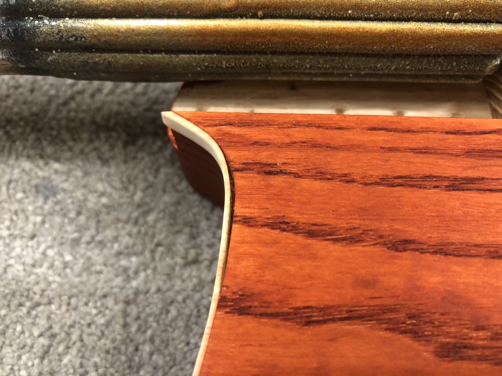 A close up on the previous photo, showing how just where the top line of the guitar curves down and up again from the neck pocket you can see the binding has come away from that corner for a length of about an inch or so.