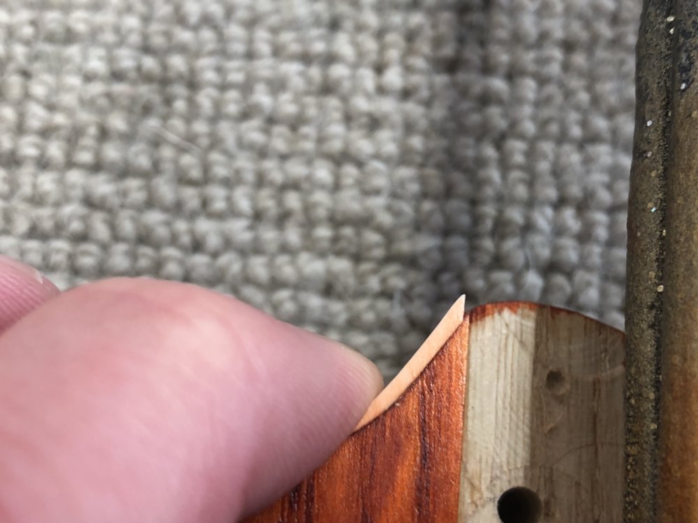 A close up photo of my finger pressing the binding back into place on the guitar body, and you can see that the binding no longer is long enough to go all the way to the neck-pocket, instead stopping a millimetre or so before.