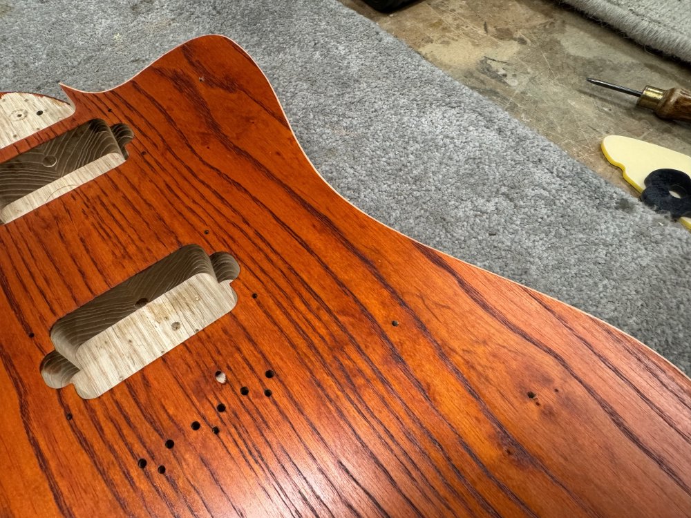 A photo of the front of the guitar, where if you look very closely you can just about see three small 2mm-ish holes have been drilled corresponding to where we saw the acrylic templates fit on the back.
