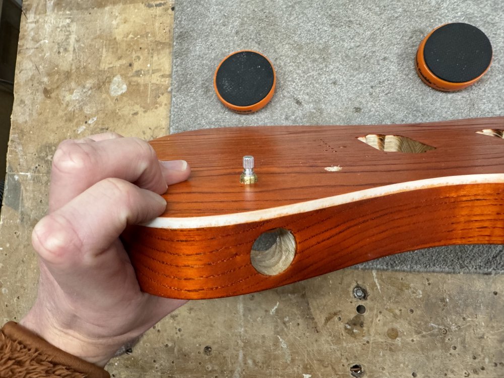 A photo of that same phone in the guitar, but now the stop end of a potentiometer can be seen sticking up through the hole. In reference to the next section, here you can also see that the supposedly white plastic binding along the side is splattered in places with orange dye.