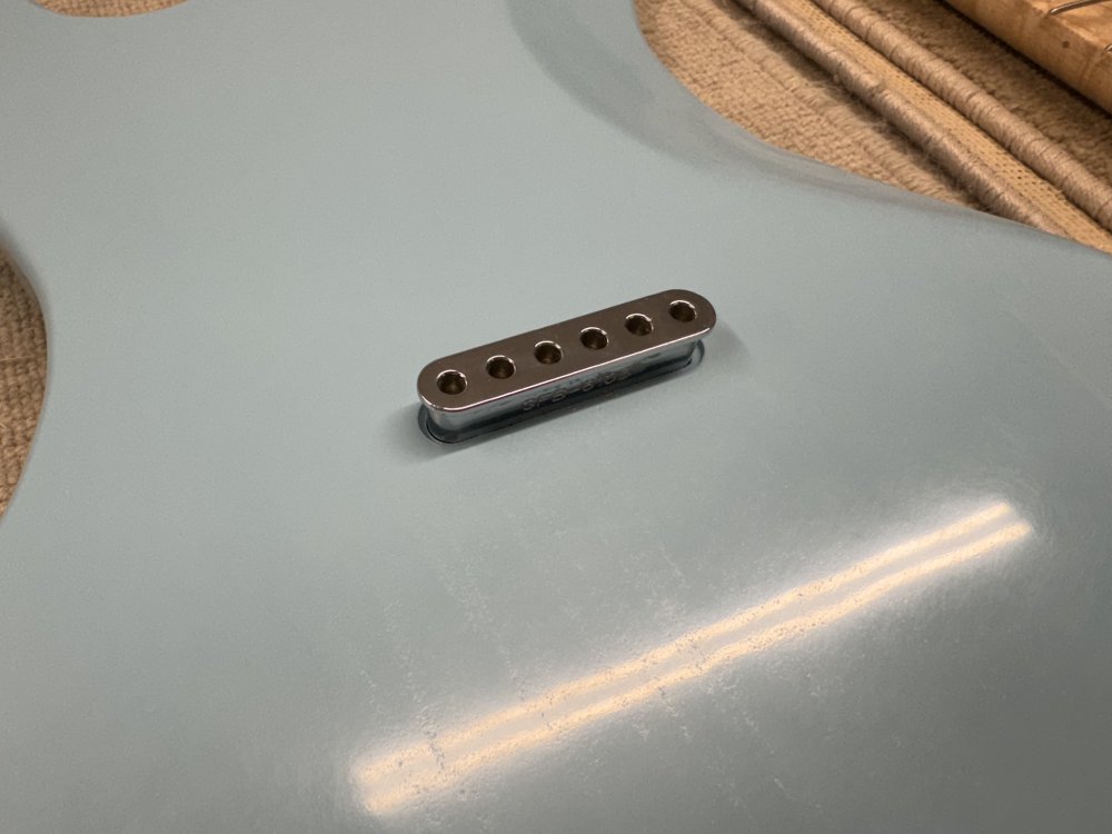 A close-up photo of the back of the guitar body showing the string-ferrule-block sitting over the spot where it should slip into the pocket on the back of the guitar.