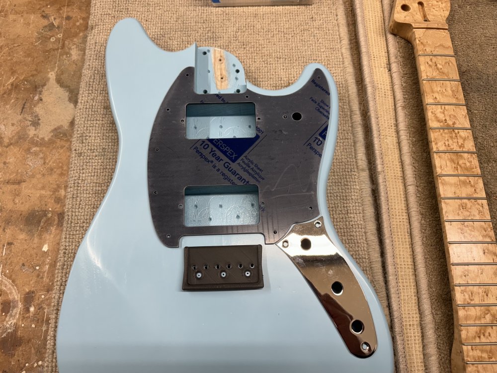 A top down view of the body with the pick-guard and bridge in place. Between the bridge and the pick-guard there is an uneven recess that has a narrow gap on the sides, but a much larger gap on the top, and looks odd due to these different proportions.