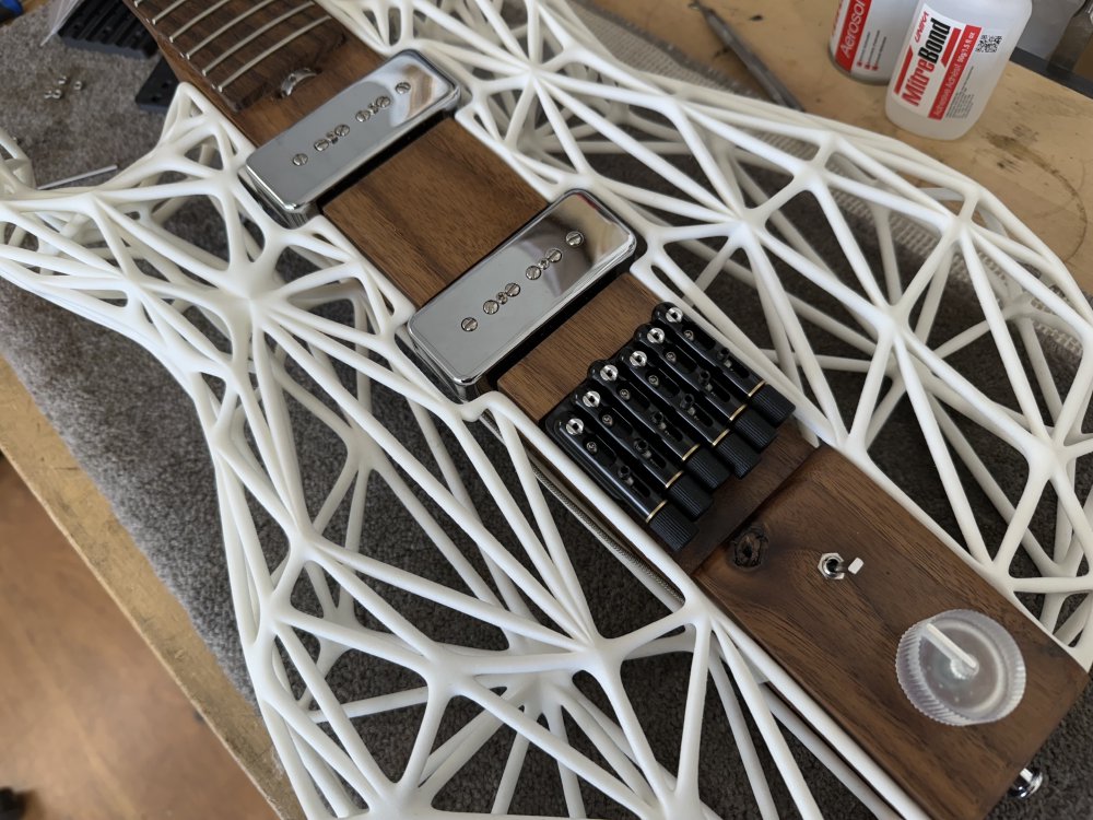 A photo of the mid-section of Älgen, showing the pickups and bridge of the guitar. The bridge is that of a headless guitar design, so not only are the strings anchored here, but it has knobs for each string to let you tune it.