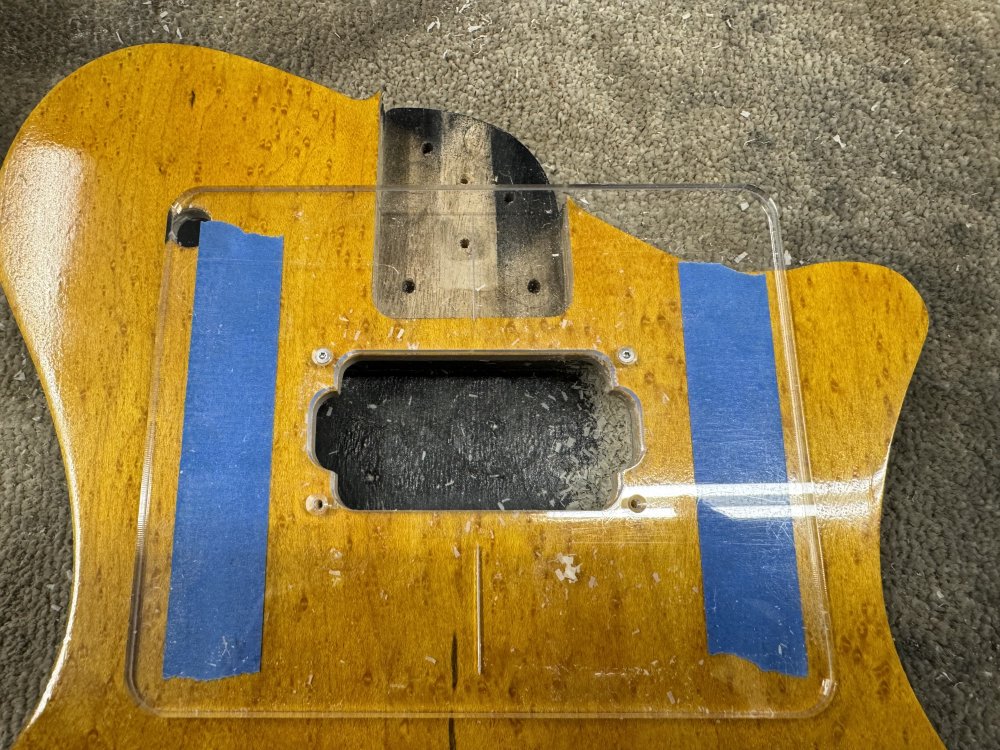 A photo of the guitar body now with the router removed, showing the template for the pickup mount and the top of the guitar being flush with the template after being cut.