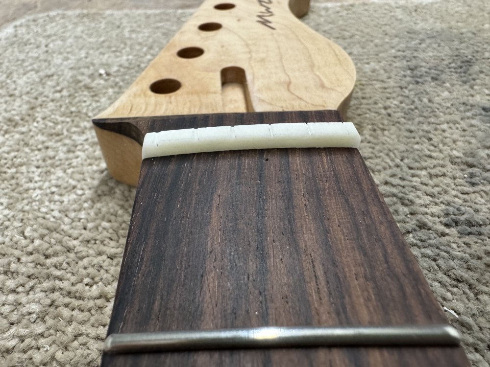 A photo of the nut back in the guitar neck ready for strings to be added to it.