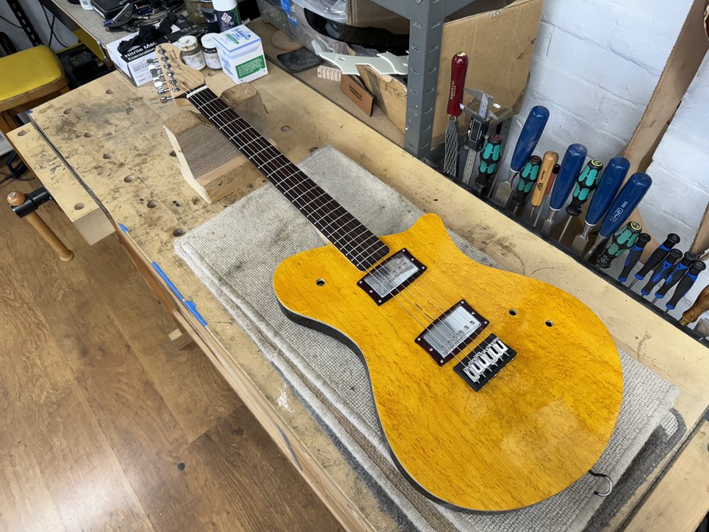 A photo of a guitar on a workbench with strings on it! Some bits are still missing, like the volume control and pickup selector switch.