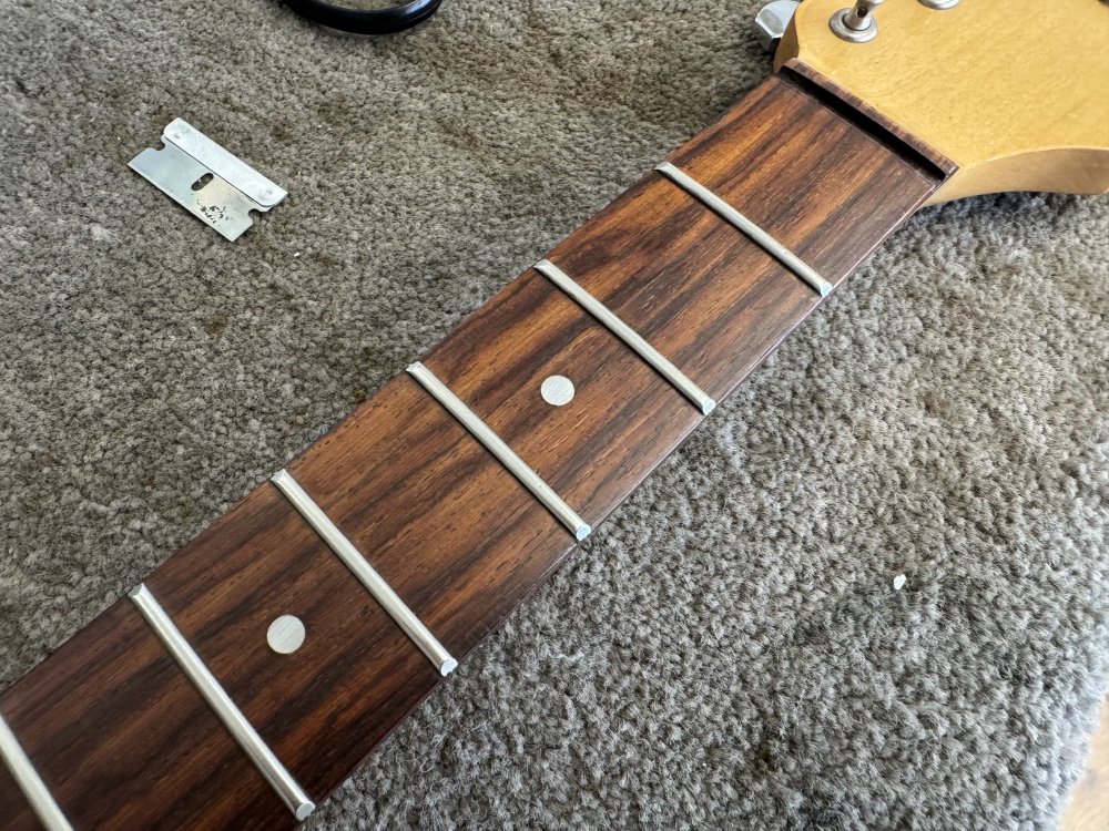 A photo of the same fretboard, with all the marks removed and the wood looking shiny and new.