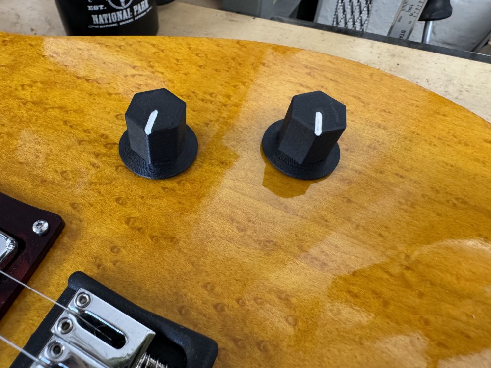 A photo of the two 3D-printed knobs mounted on the guitar, and on the top of each is now a clear white line to indicate the direction it is turned.