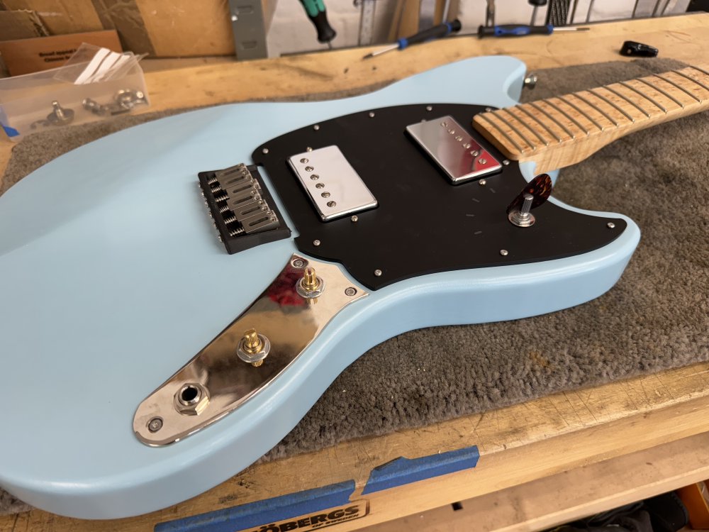 A photo of the guitar body with both the pick-guard and the chrome control plate mounted with everything in place.