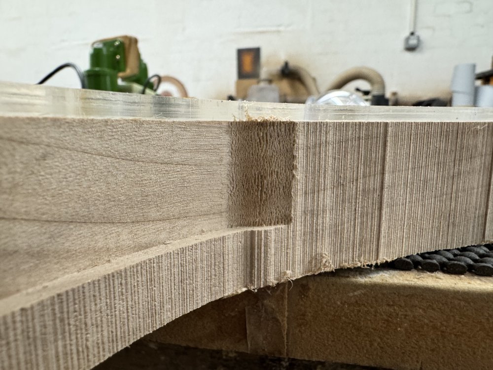 A close-up photo of a strip on the body where the router has been applied, and it's given a very clean cut for most of the pass, but right at the end as the router moves away from the body the wood is all damaged as the router bit was cutting against the grain.