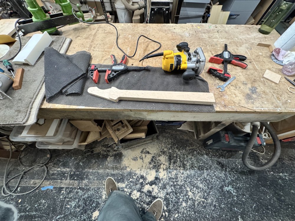 A wide-angled photo showing the work in progress neck that has been trimmed, now unclamped, and on the floor is a large amount of wood dust.