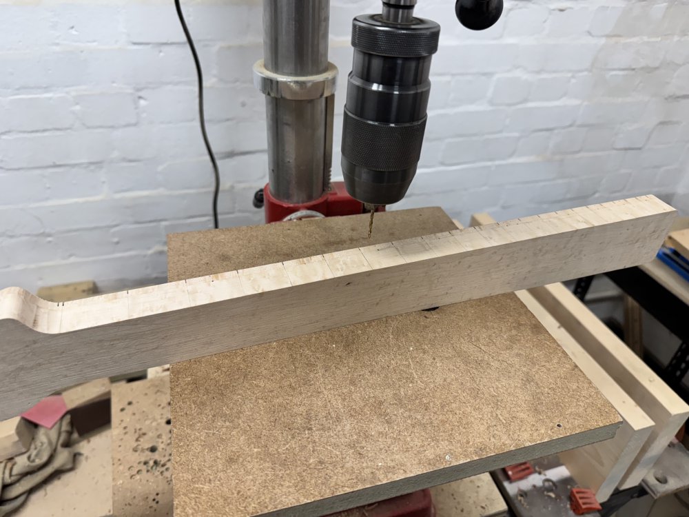 The work in progress guitar neck now sits on its side again, but this time on the table of a pillar drill.