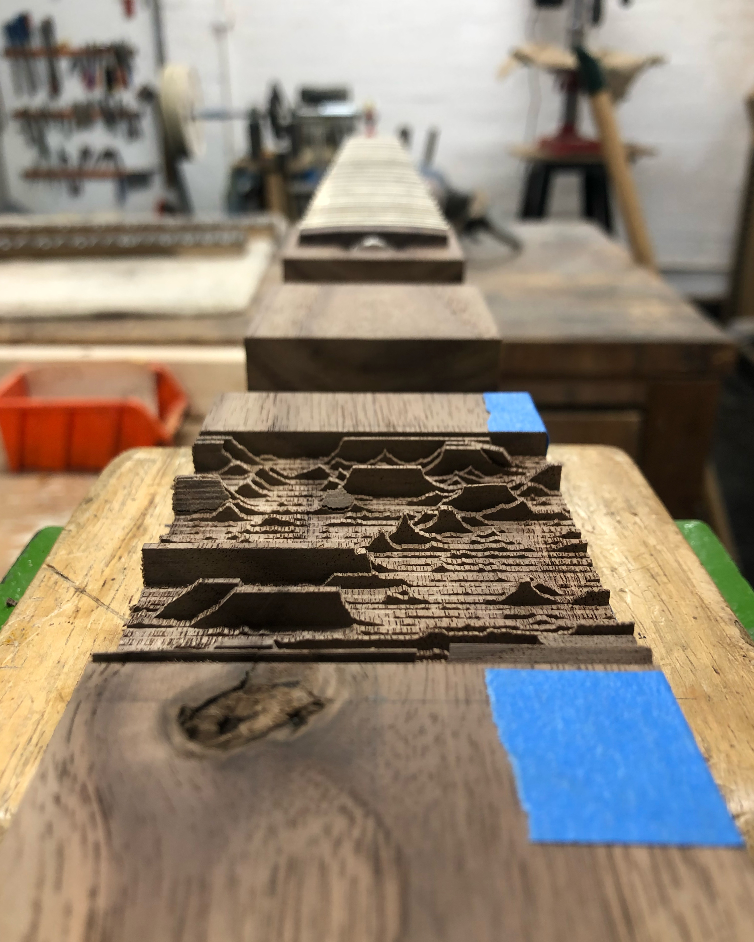 A photo of the view down a length of walnut wood, into which has been sliced a number of thin layers of wood that were then broken, so it now looks like a mountain range.