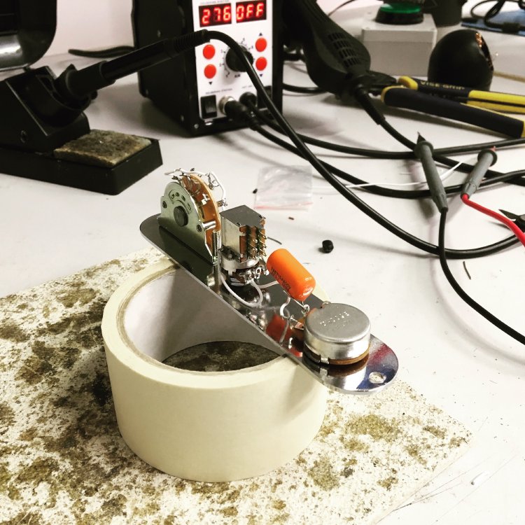 The control plate and wiring harness for a telecaster on an electronics workbench.